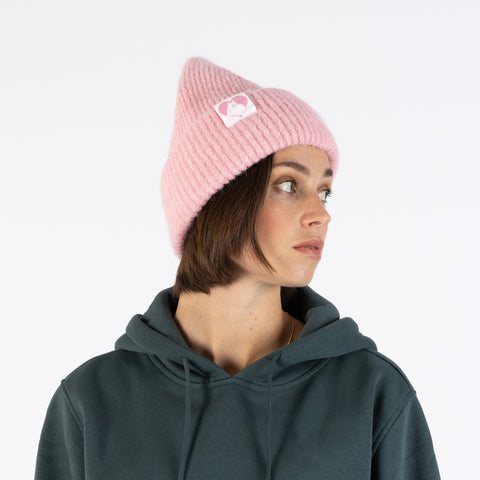 1. Woman wearing pink ribbed beanie with Moomin character patch, side view