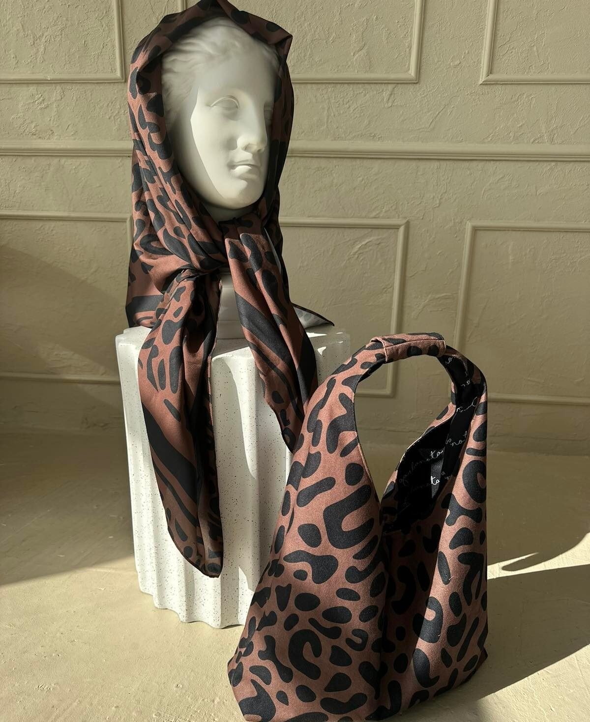 8. Woman with Garbanota Moon Bag in classic leopard print, styled with a grey blazer and jeans