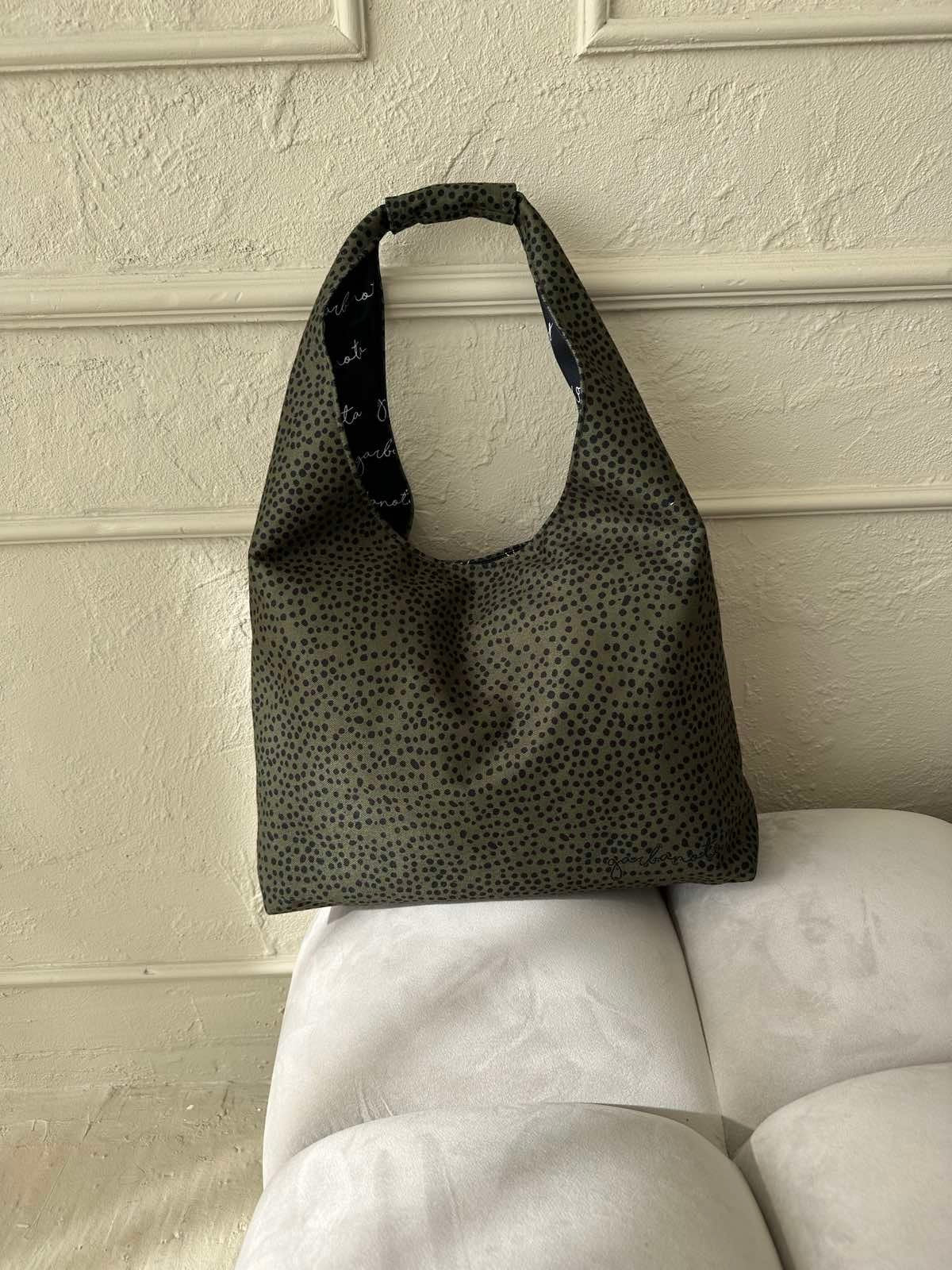 1. Garbanota Moon Bag Heart in khaki polka dots displayed on a light sofa, showcasing its spacious design and unique pattern lining