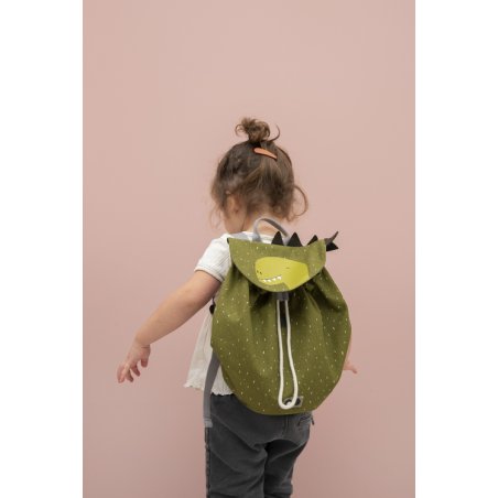 1. Child wearing green dinosaur-themed mini backpack with drawstring closure, facing away against a pink background