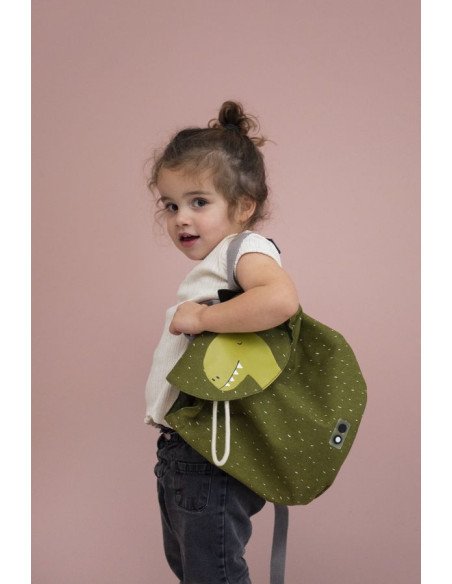 1. Child wearing green dinosaur-themed mini backpack with drawstring closure, standing against a pink background