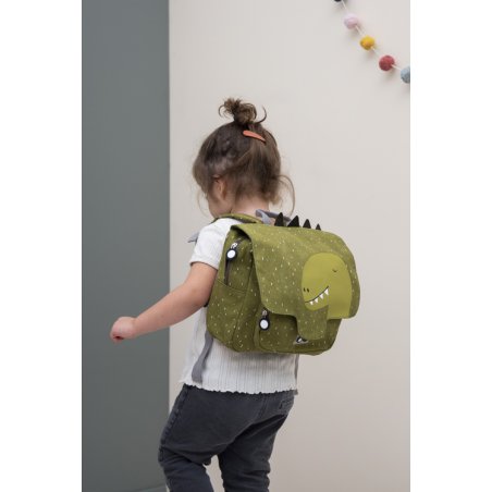 1. Child wearing green Mr Dino school bag with dinosaur design, indoor setting