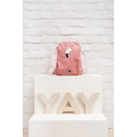 1. Pink flamingo-themed backpack displayed on a white pedestal with 'YAY' letters, against a brick wall