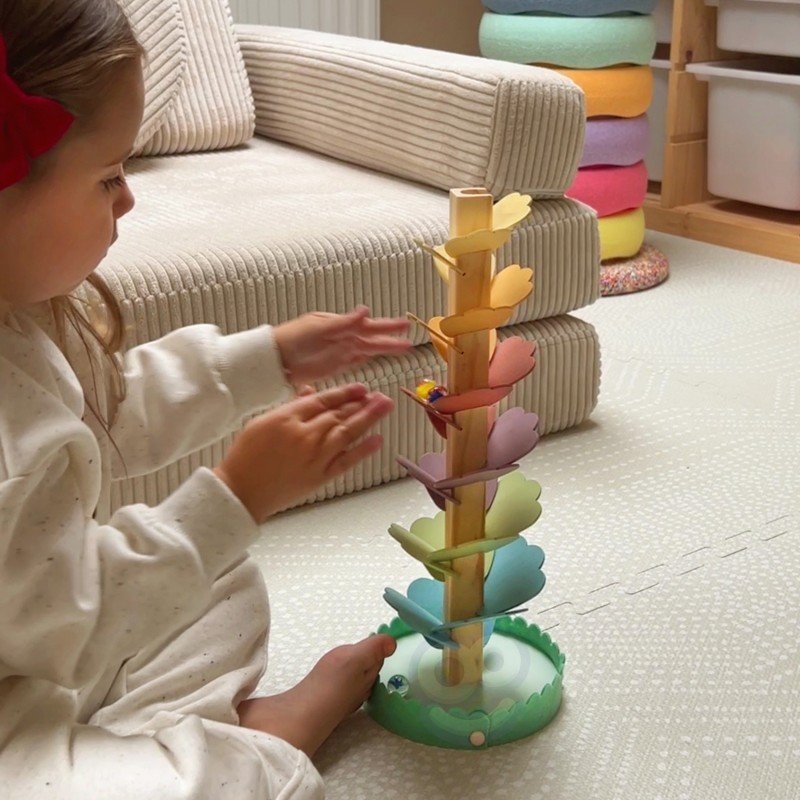 3. Child clapping hands while playing with colorful wooden ball track on carpet