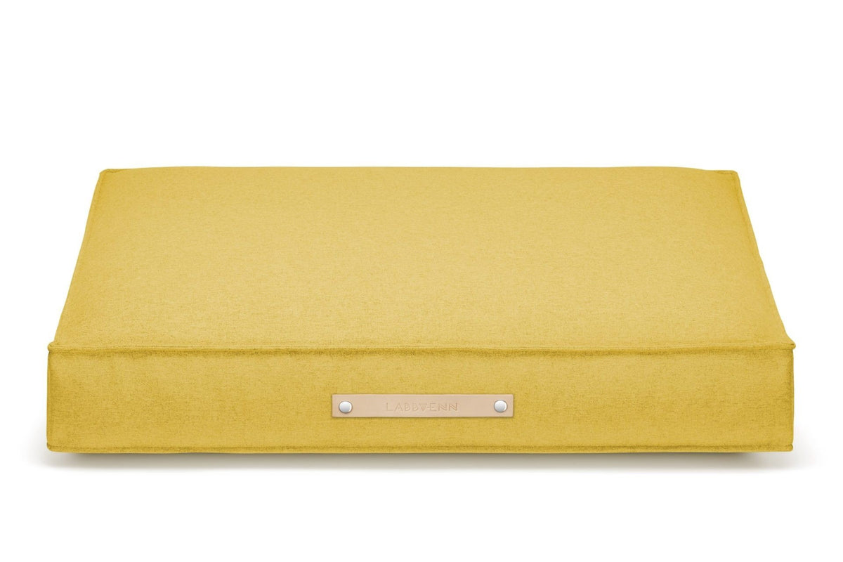 2. Labbvenn Møvik Cushion in honey color with leather belt and logo, shown in studio setting