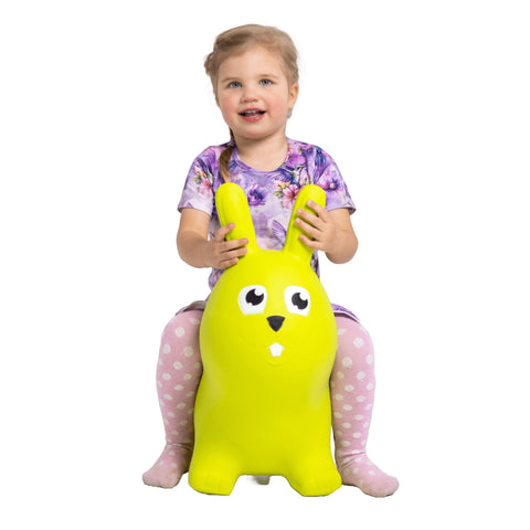 1. Young girl sitting on green bunny hopper toy wearing purple floral dress and pink polka dot leggings