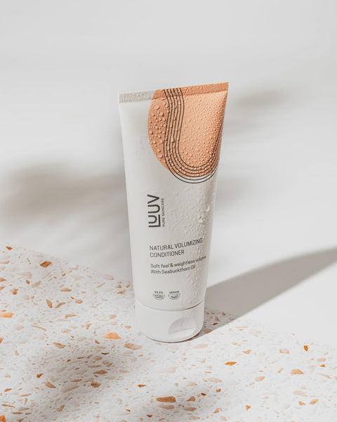 3. LUUV Natural Volumizing Conditioner with sea buckthorn oil, featuring water droplets on a terrazzo surface