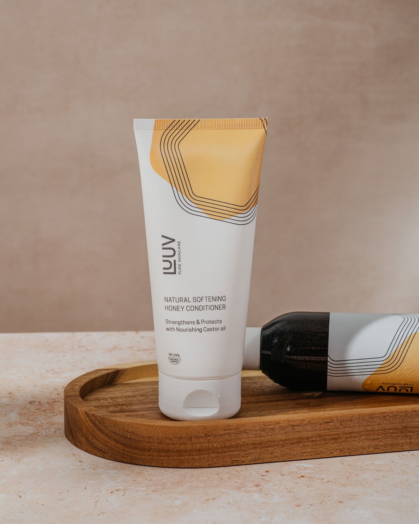 3. LUUV Natural Softening Honey Conditioner tube on wooden tray, emphasizing nourishing castor oil and eco-friendly packaging
