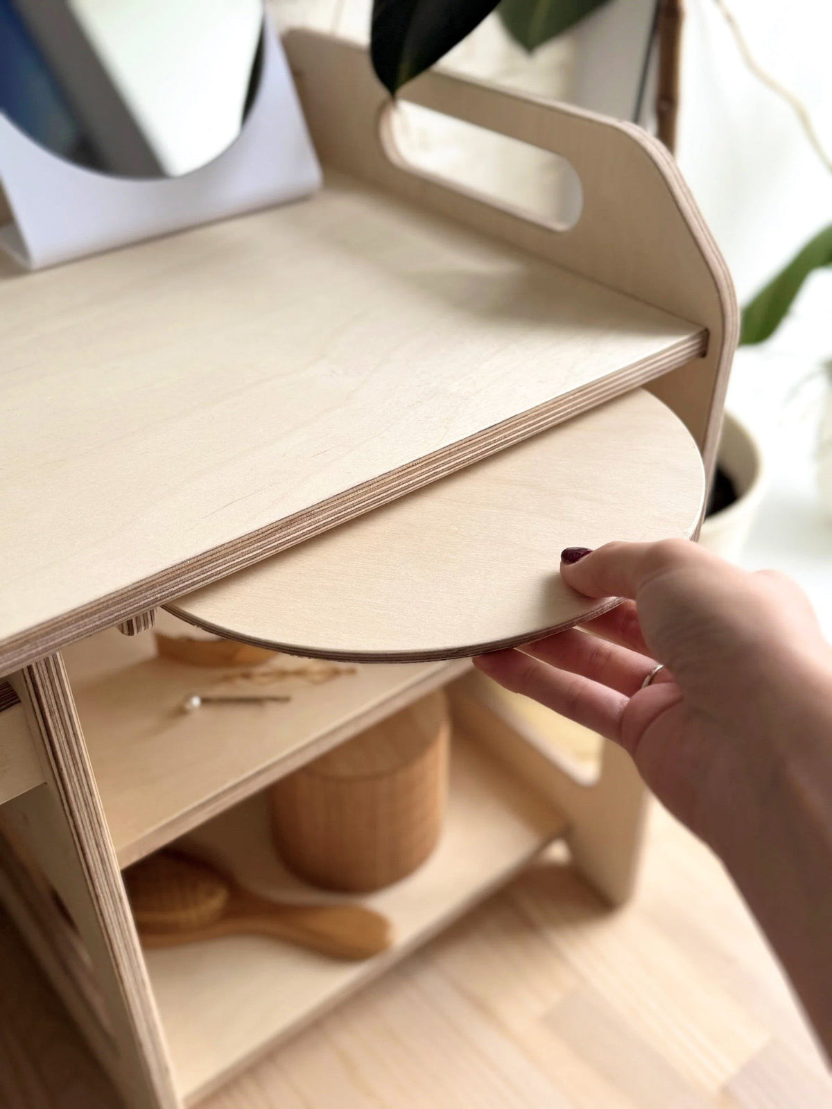 11. Hand placing wooden cover on Montessori washbasin with storage