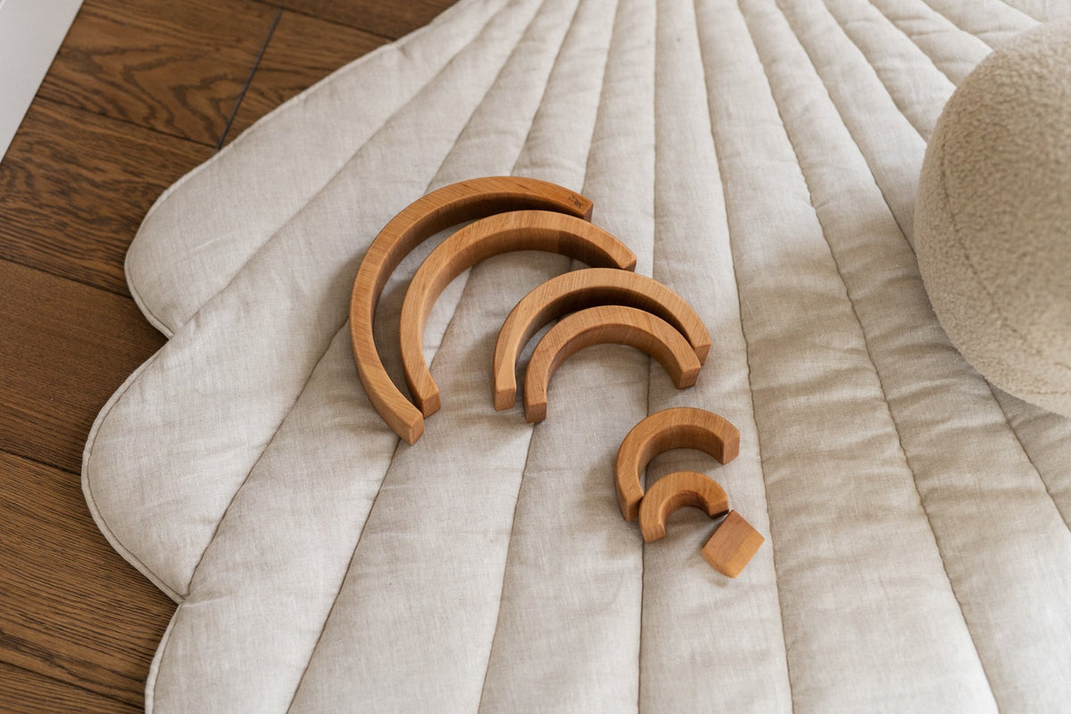 3. Close-up of organic cotton and linen shell playmat in sand color with wooden toys on top
