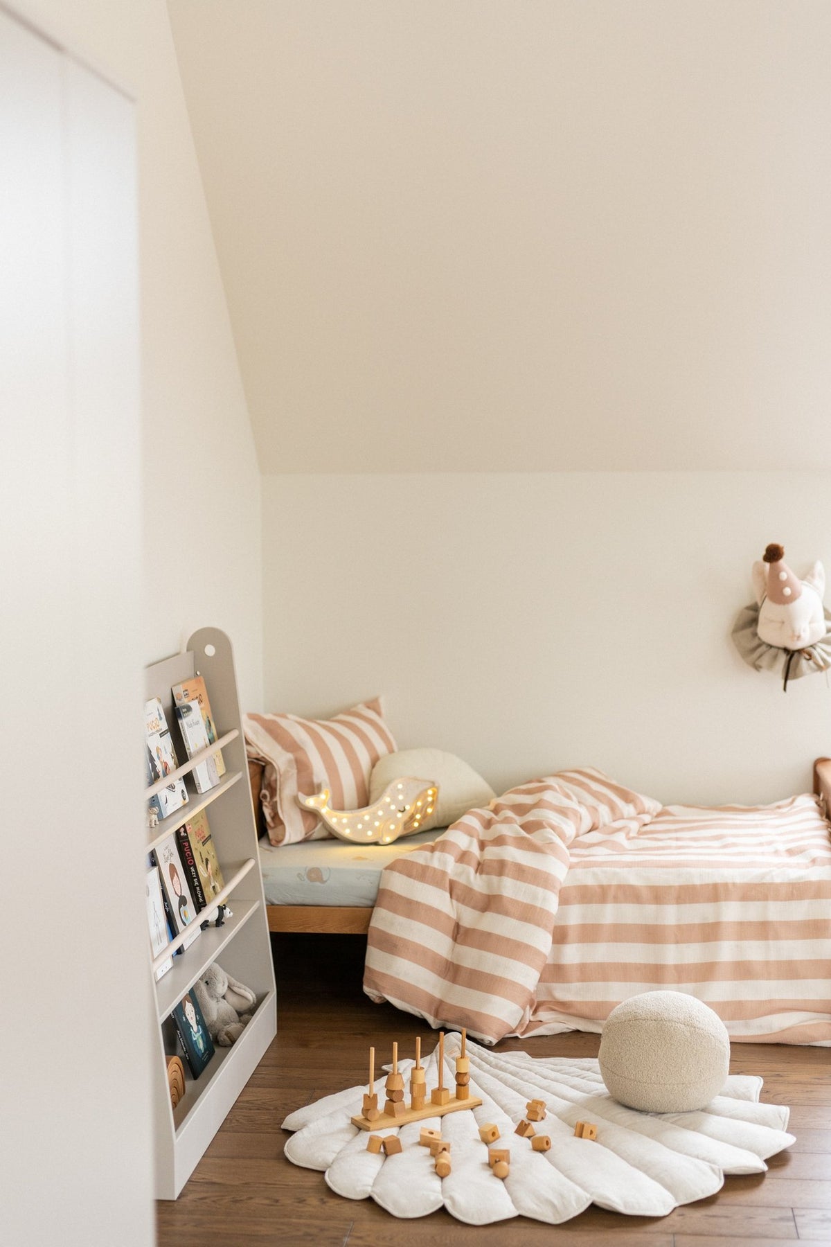 1. Organic cotton and linen shell playmat in sand color in a child's bedroom with striped bedding and toys