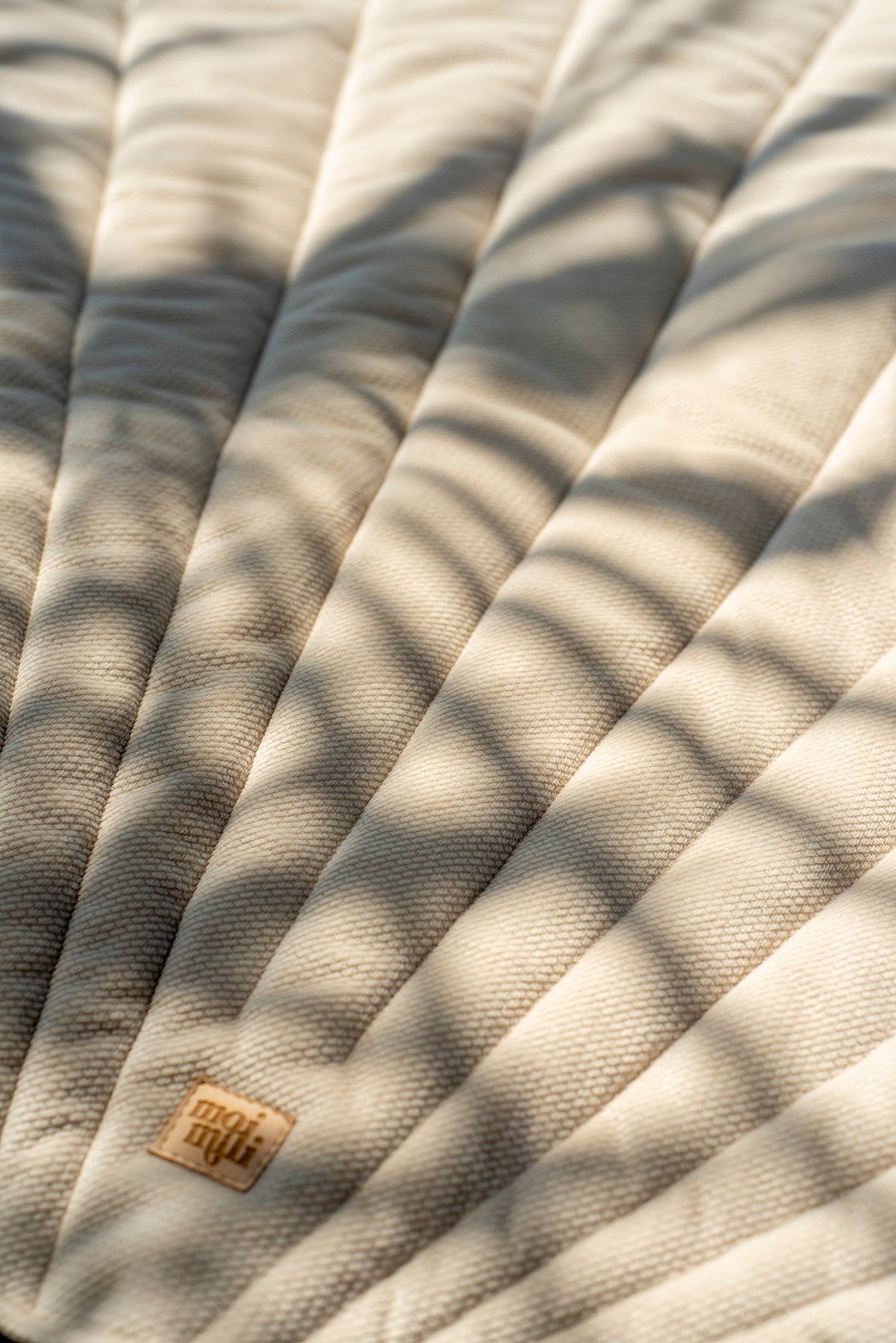 9. Close-up of beige ginkgo leaf-shaped playmat with shadows and logo detail