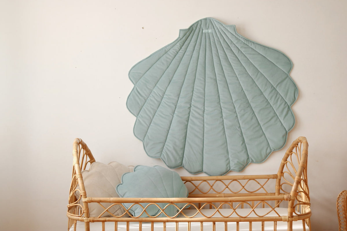5. Mint green shell playmat hanging on wall with matching pillows in wicker crib