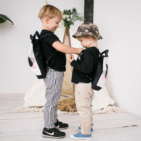 1. Two young boys wearing Muni Panda backpacks in a playful indoor setting