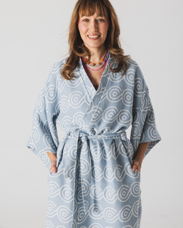 5. Woman smiling in Patulove blue bamboo kimono with swirl pattern, hands in pockets