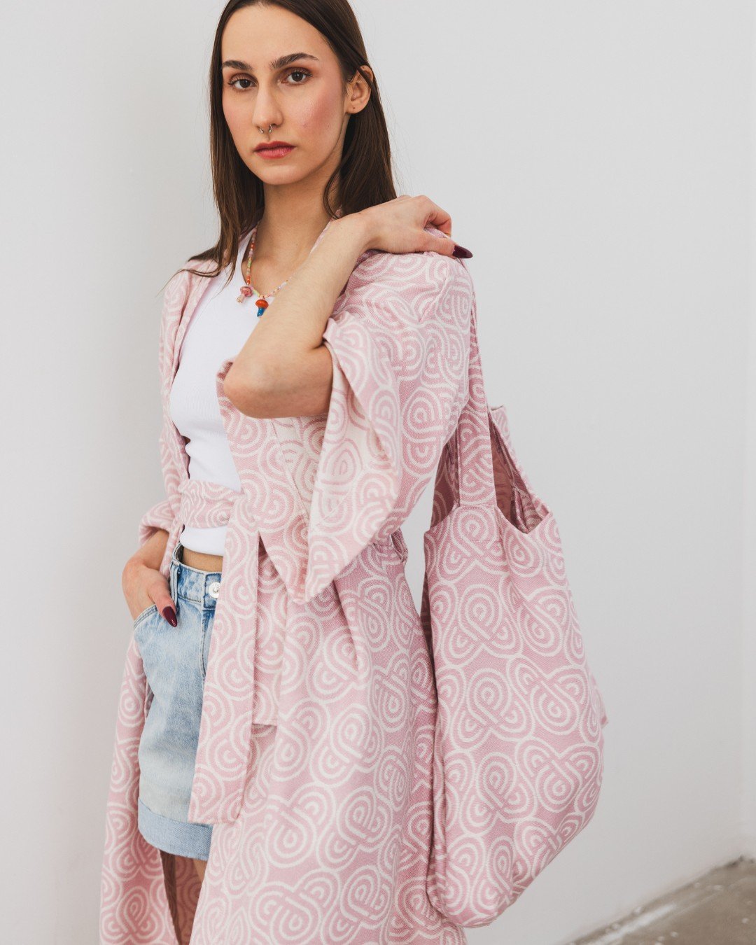 5. Woman wearing Patulove rose bamboo kimono with matching bag, styled with white top and denim shorts