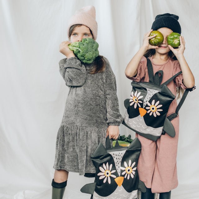 4. Two girls with Muni owl backpacks in lifestyle setting, holding vegetables