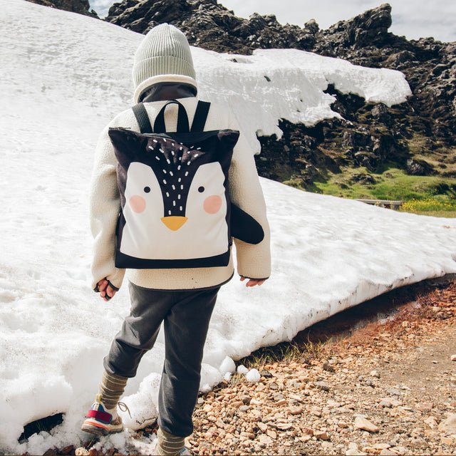 3. Child wearing Muni Penguin backpack walking in snowy landscape