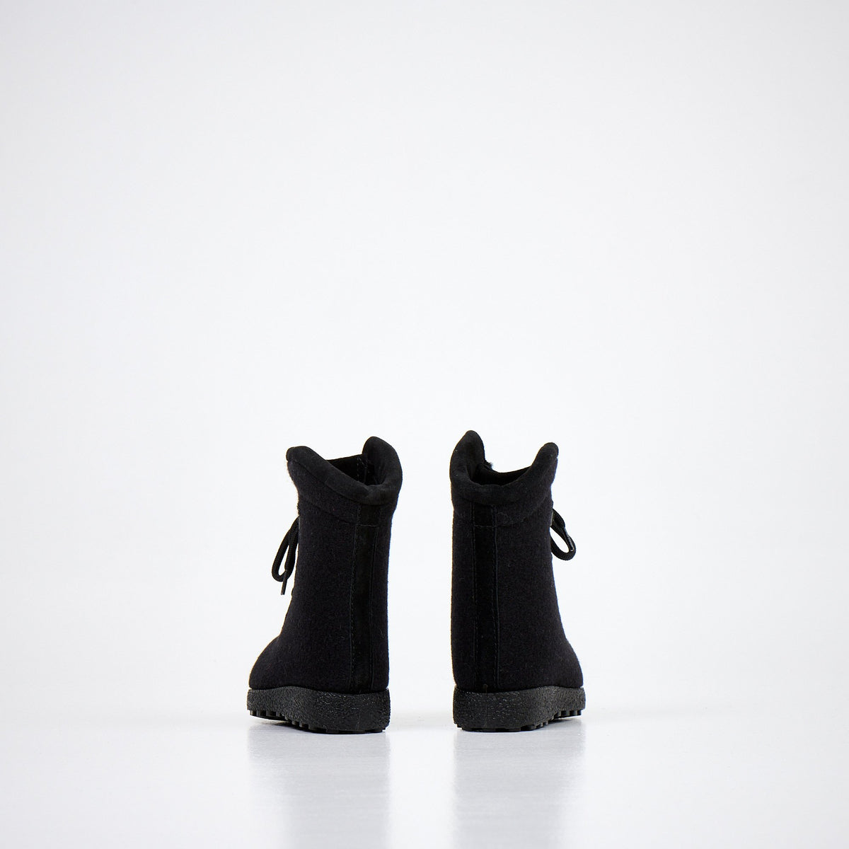 3. Pair of black kids' felt boots shown from back, highlighting heel and sole design on white background