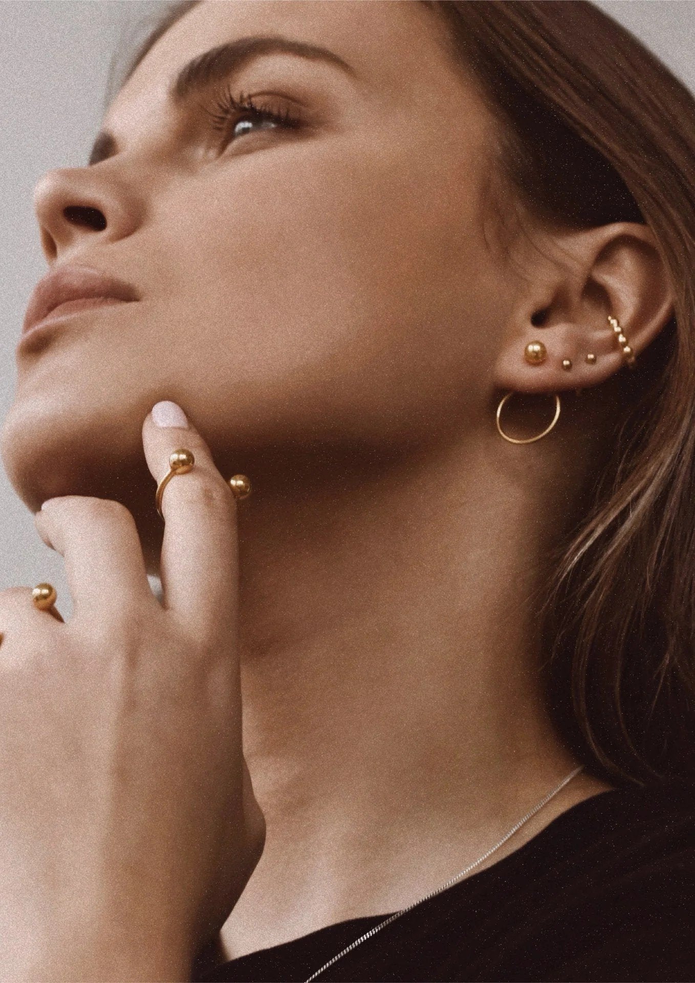 2. Women's gold pin-up earrings worn by model with additional gold jewelry, shown in lifestyle setting