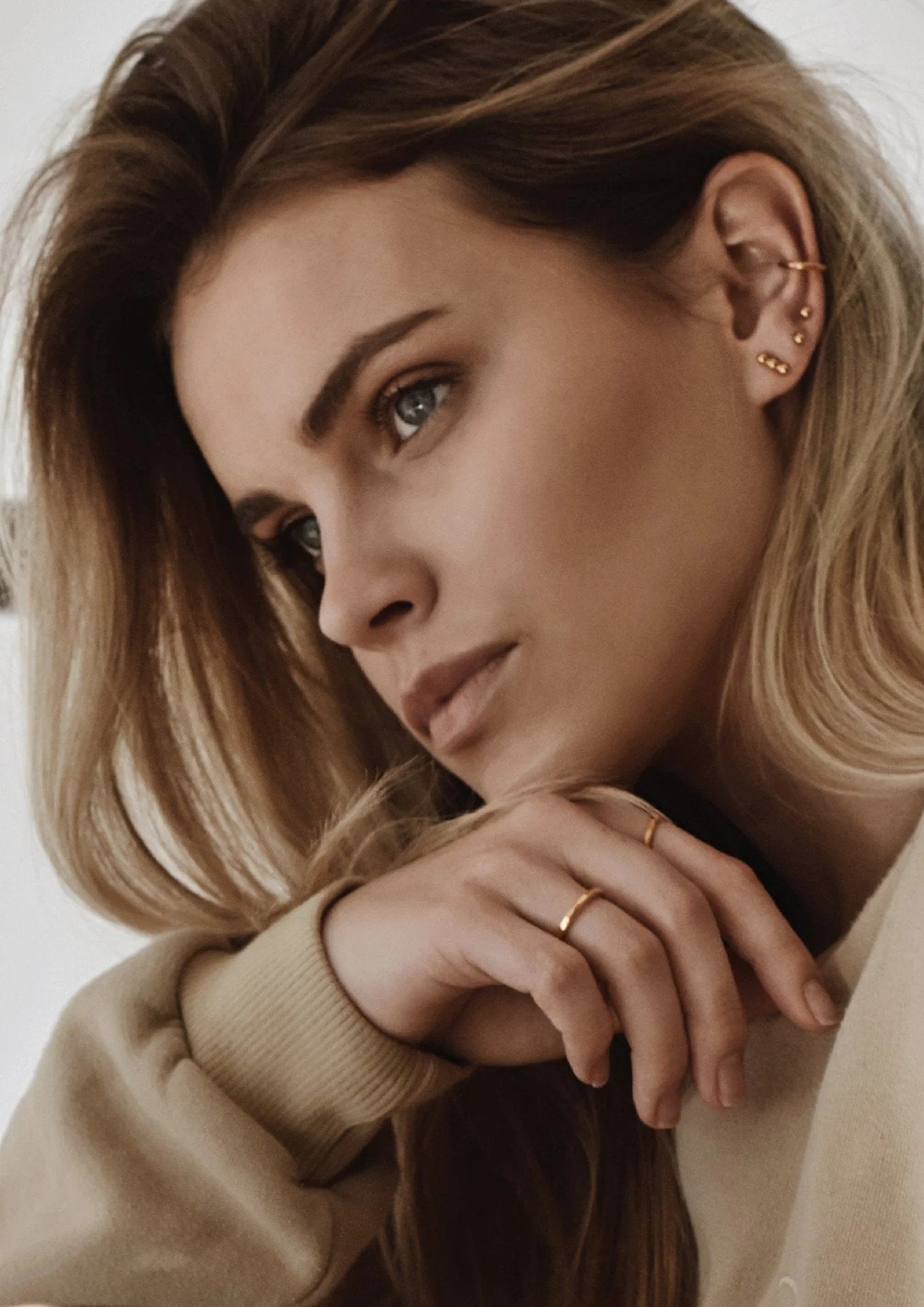 4. Women's gold pin-up earrings worn by model with multiple ear piercings, shown in lifestyle setting