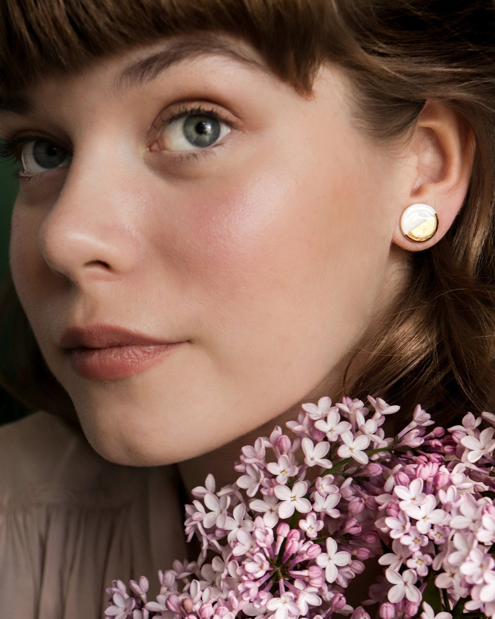 1. Woman wearing Rozenthal black and gold porcelain round stud earrings, styled with flowers