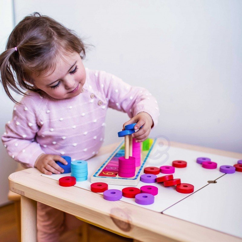 12. Child in pink polka dot sweater stacking blue rings on a wooden counting puzzle