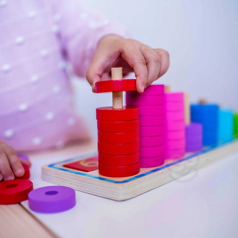 11. Close-up of child's hand stacking red rings on a wooden counting puzzle