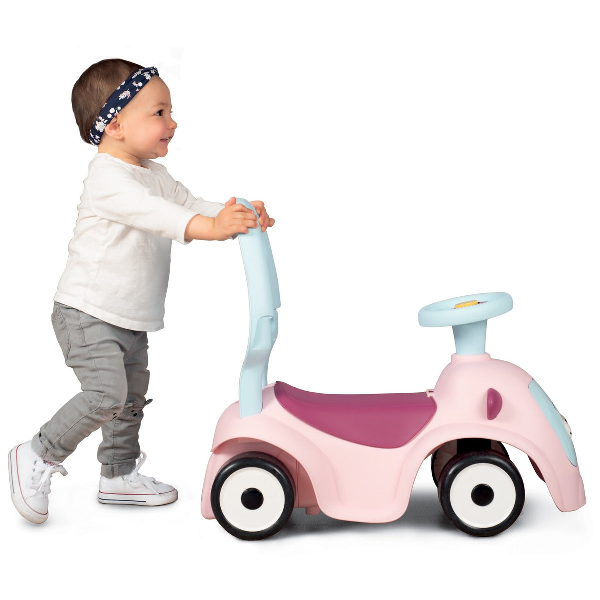 2. Toddler pushing Smoby Ride-on Maestro 3in1 in pink, used as a walker, wearing a headband and sneakers