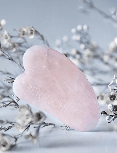 2. Berrichi Rose Quartz Gua Sha Massage Crystal styled with delicate flowers, showcasing heart-shaped design and natural pink hue