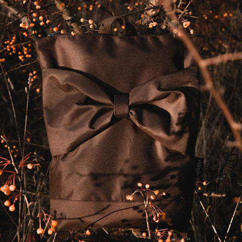 4. MUNI waterproof brown backpack with bow displayed outdoors among autumn foliage