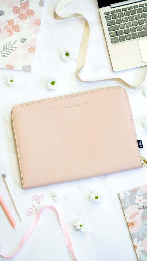 2. SEIK pink laptop sleeve next to a laptop, surrounded by flowers and stationery