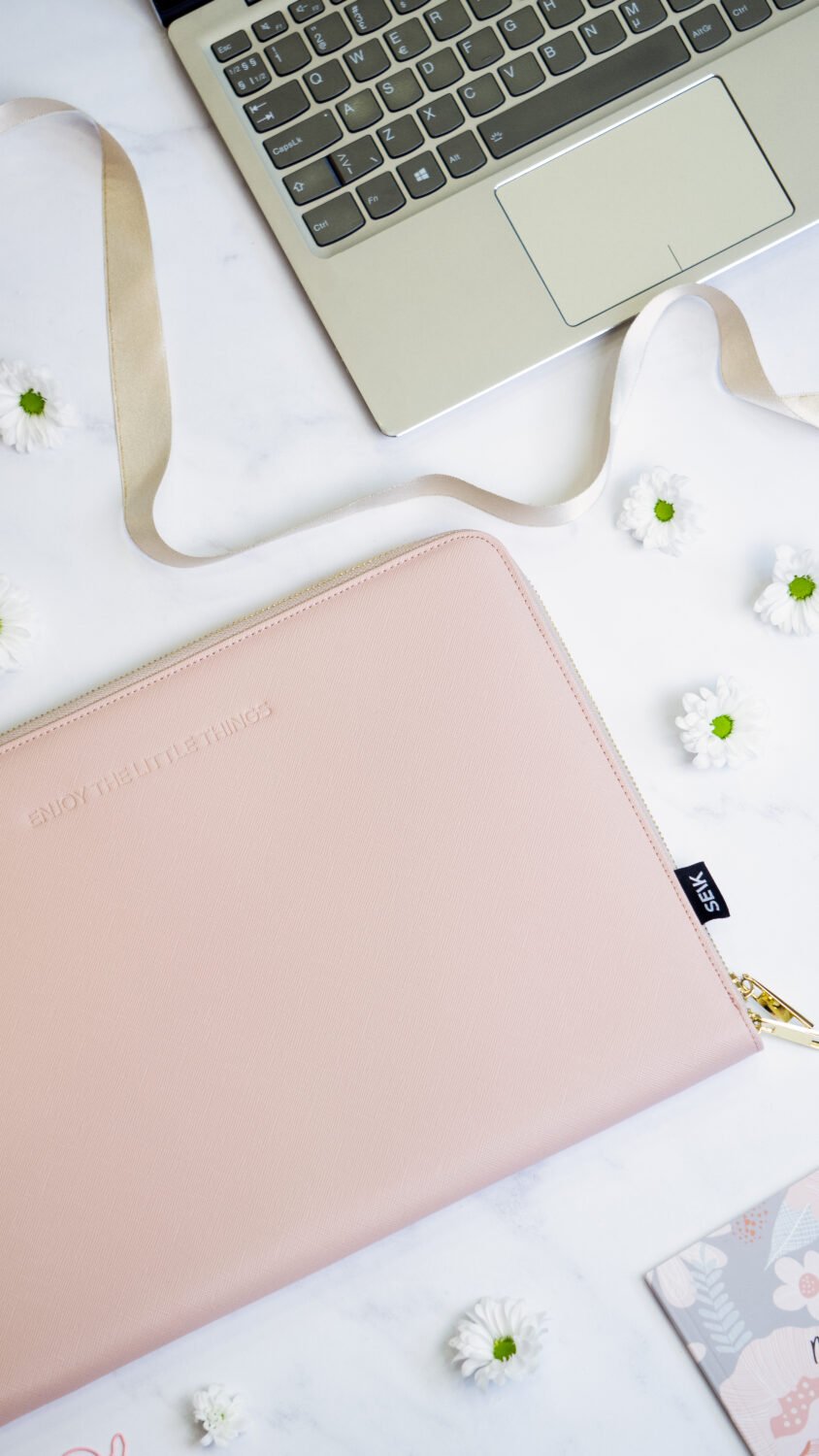 11. SEIK pink laptop sleeve on a desk with floral accents and a laptop