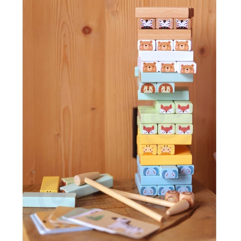 12. Shaky Tower game setup with pastel animal blocks, wooden hammers, and cards on a wooden surface