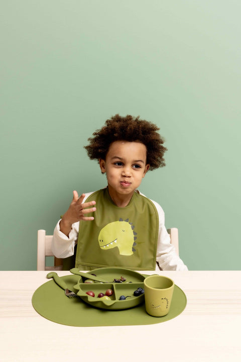 1. Child enjoying meal with green silicone cup and matching dinosaur-themed dining set