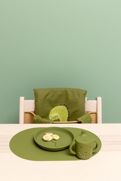 1. Green silicone plate with dinosaur design on a table setting with matching cup and placemat, ideal for children's mealtime