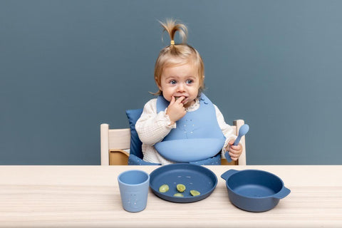 1. Toddler using Trixie Baby blue silicone plate and cup set at a wooden table
