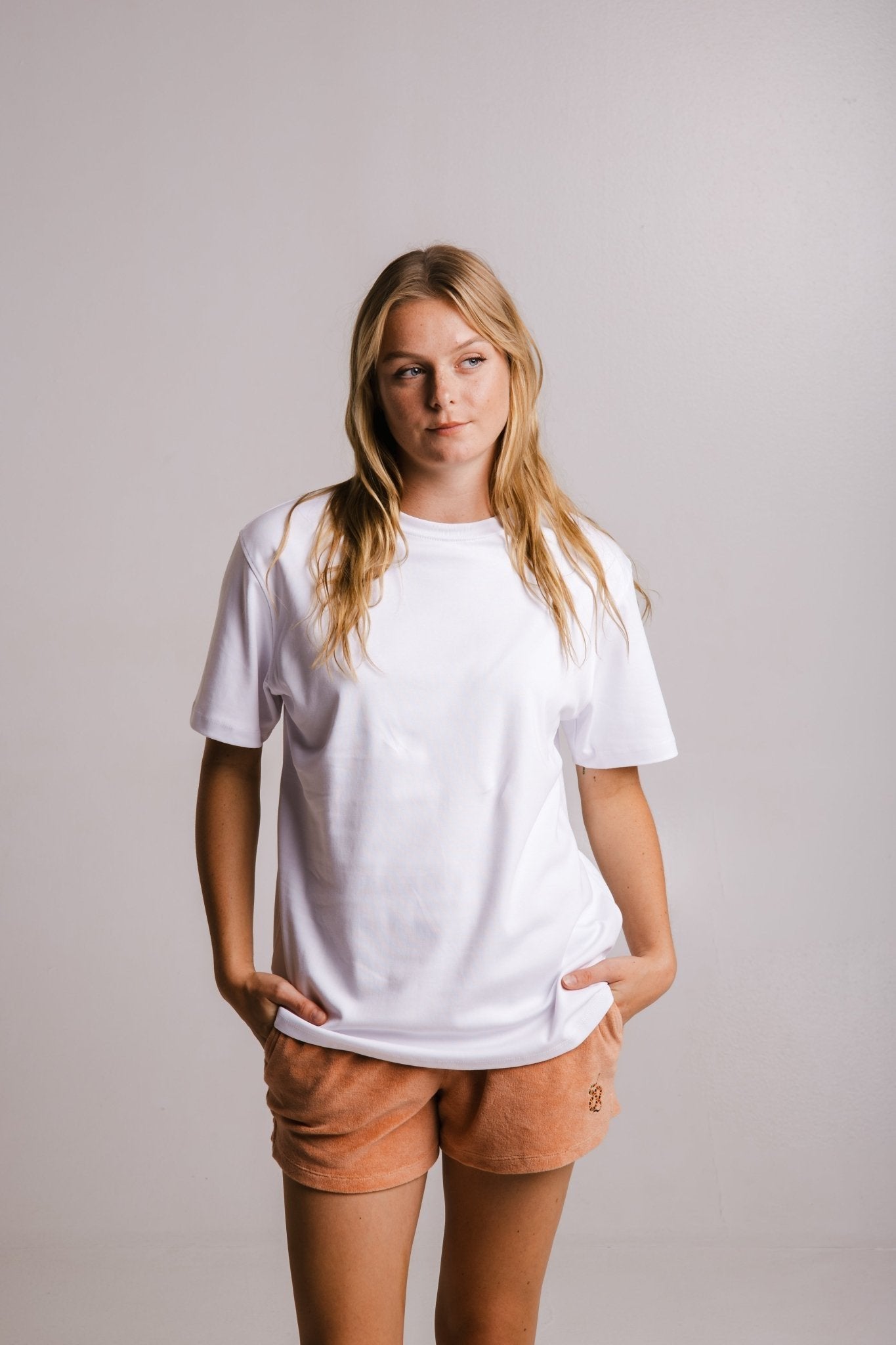 1. Women's white heavy t-shirt by Sossu, styled with peach shorts in studio setting