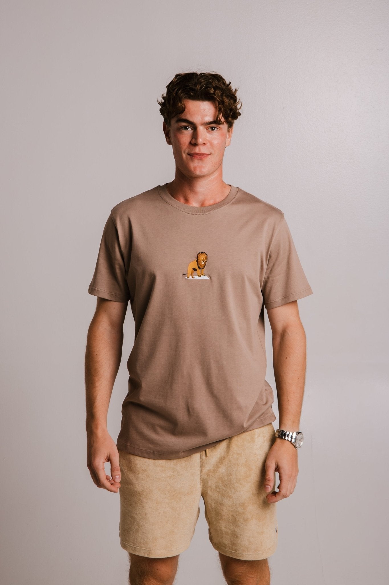 1. Unisex Lion T-shirt in Milky Brown by Sossu, worn by male model, showcasing embroidered lion detail, studio setting