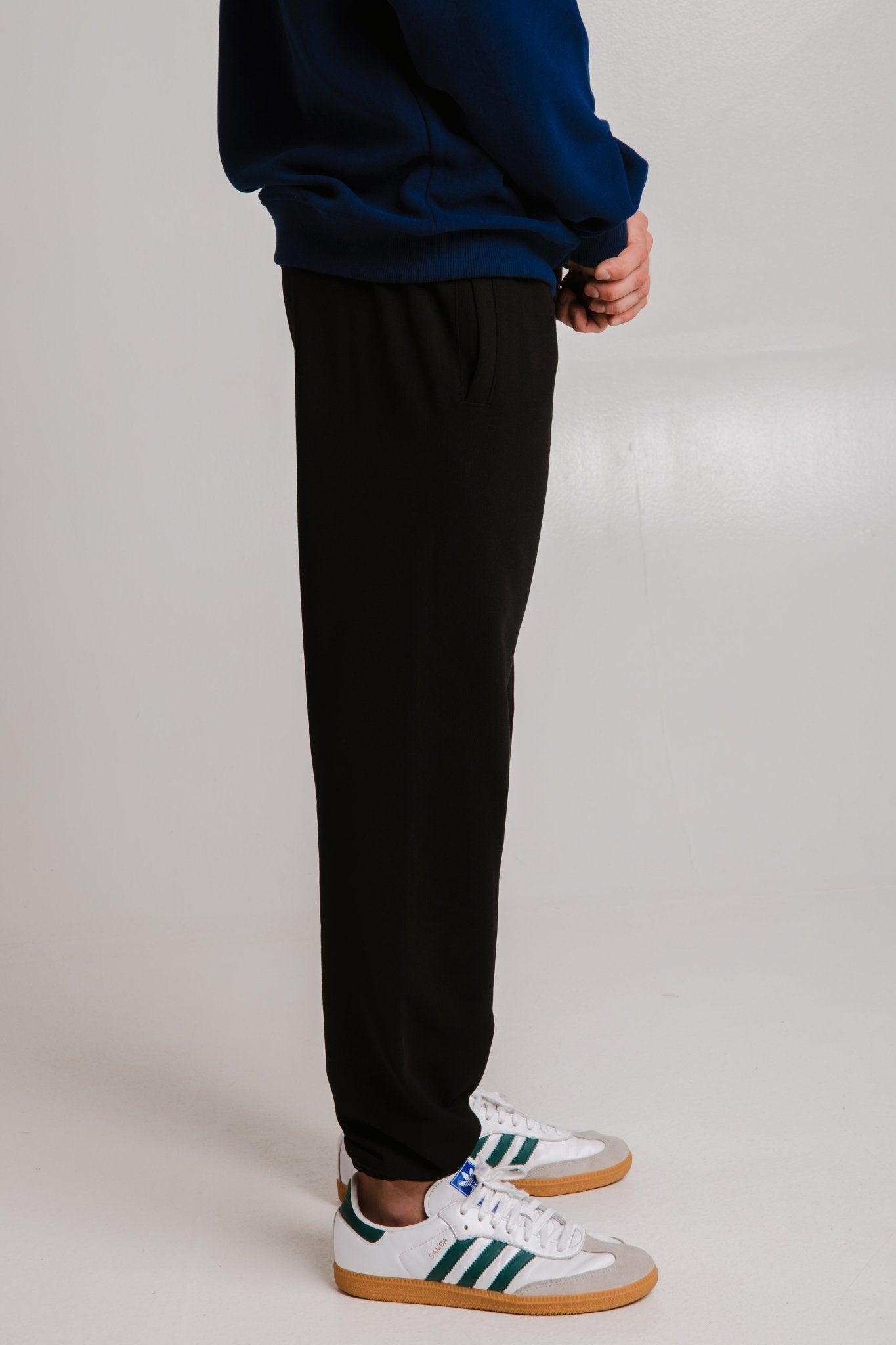 8. Unisex black Panda Soft Fleece Sweatpants by Sossu shown in side view with sneakers