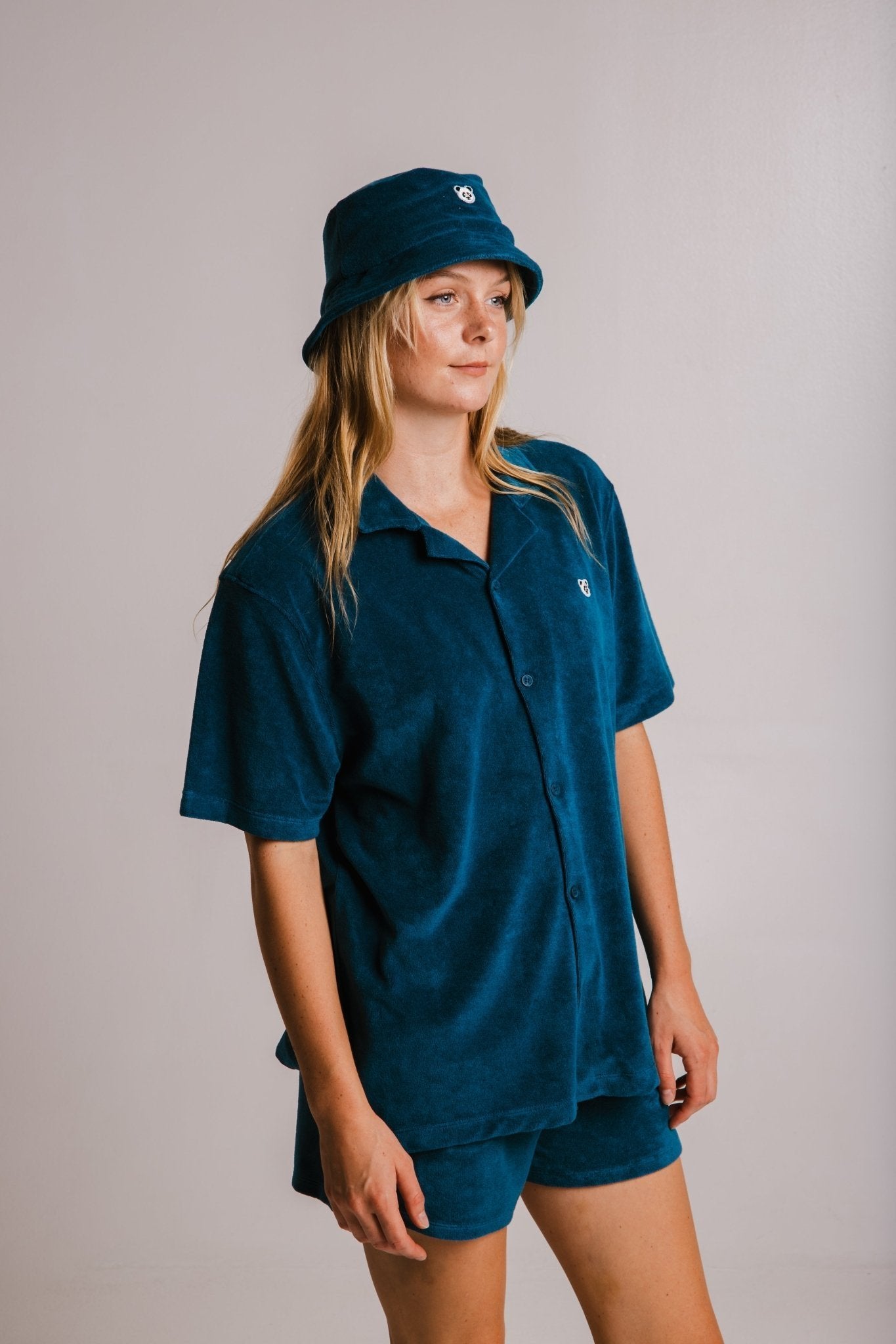 1. Women's unisex Panda Terry Shirt in navy blue by Sossu, styled with matching shorts and bucket hat in studio setting