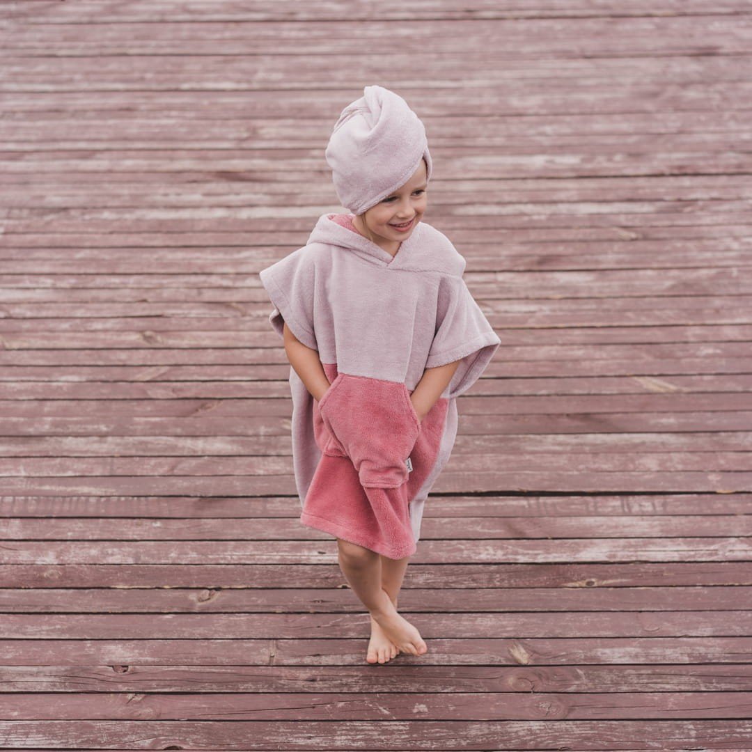 1. Child in pink Surfbunny bath poncho with bunny ears walking on wooden deck