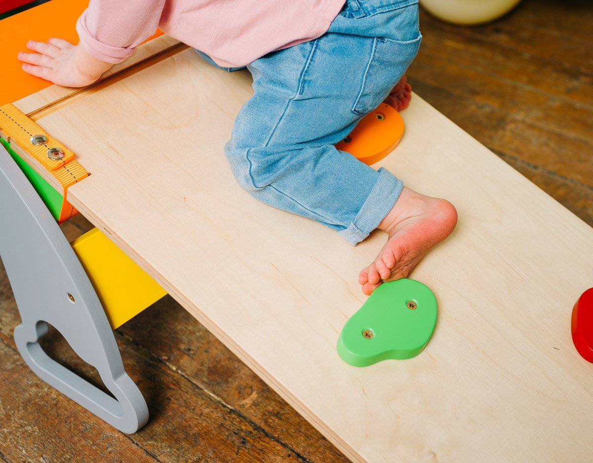 3. Close-up of child climbing on wooden board with colorful holds
