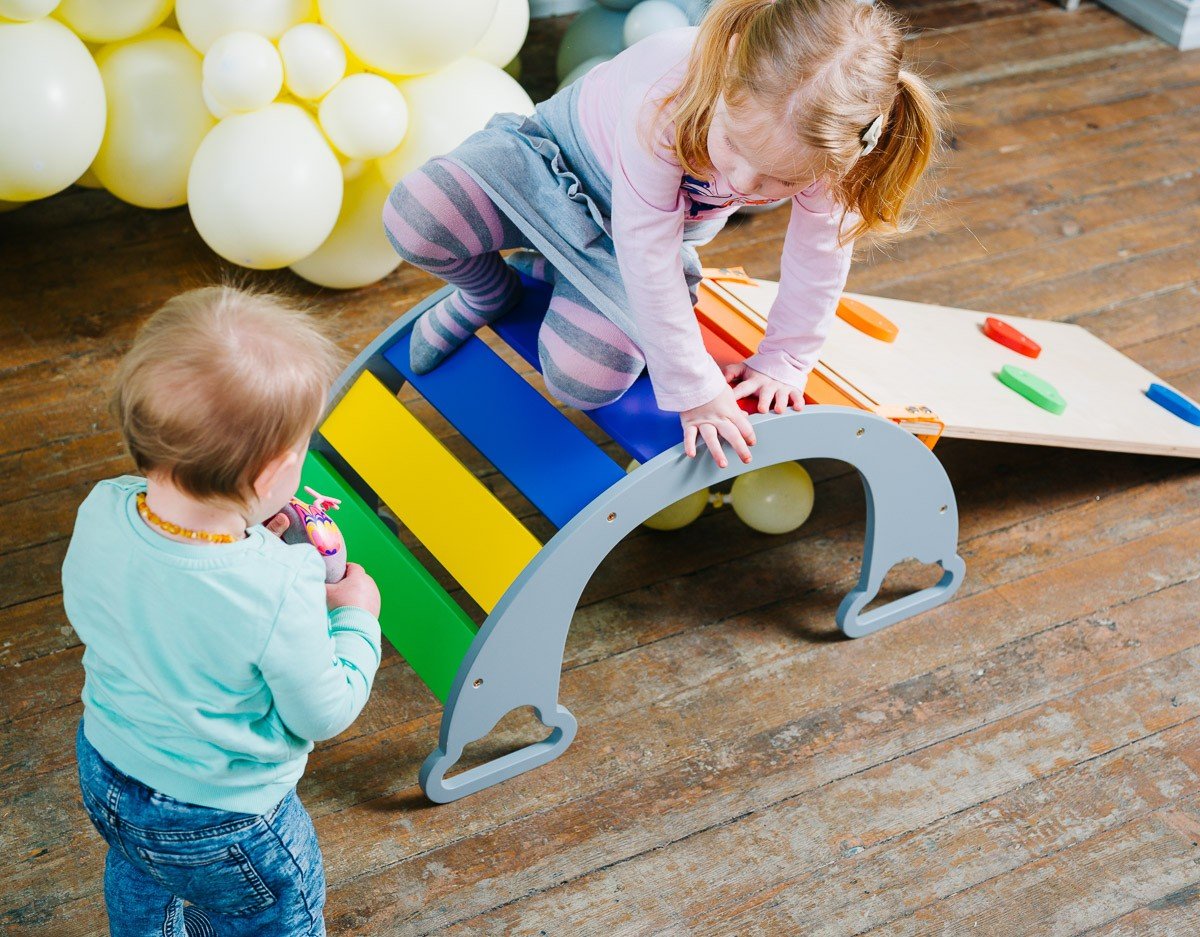 1. Two children playing with colorful rainbow climber and climbing board