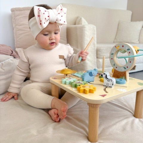 1. Toddler playing with Woopie Let's Go Green 5-in-1 wooden activity table on beige carpet
