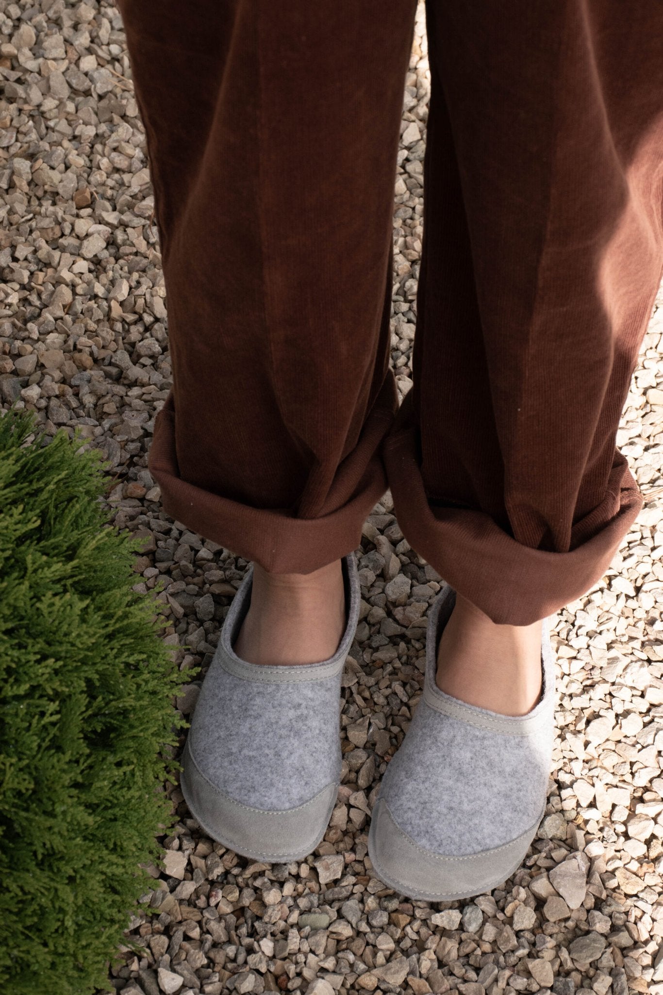 1. Unisex gray felt barefoot indoor slippers by Omaking worn by a model on gravel path