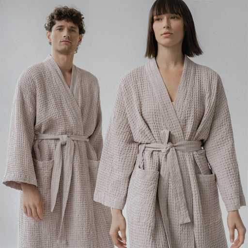 1. Man and woman wearing powder-colored honeycomb waffle bathrobes with adjustable waist ties and pockets, standing in a studio setting