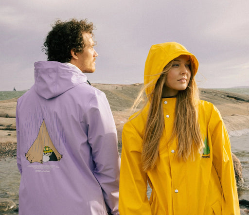 1. Unisex Moomin Adventure Rain Jacket in lilac and yellow worn by male and female models on rocky terrain