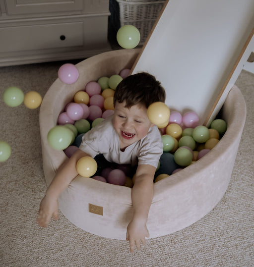 1. Child playing in beige MeowBaby foam ball pit filled with pastel balls in a cozy room