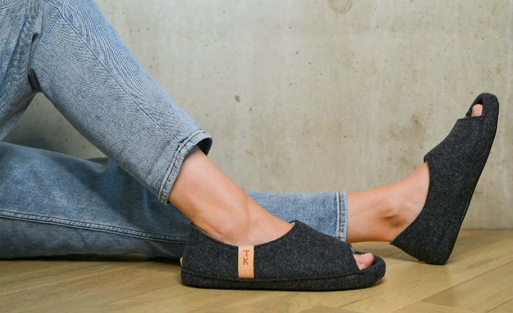 1. Women's TOKU Bern Slippers in dark gray lambswool, worn with jeans, showcasing open-toe design and comfort